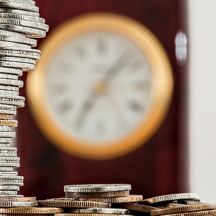 A stack of coins with a blurry clock in the background.