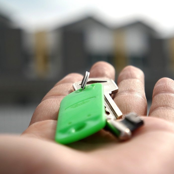 Hand with a set of house keys on a green keychain.