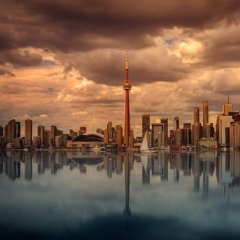 Toronto's skyline at waterfront with dark clouds above.