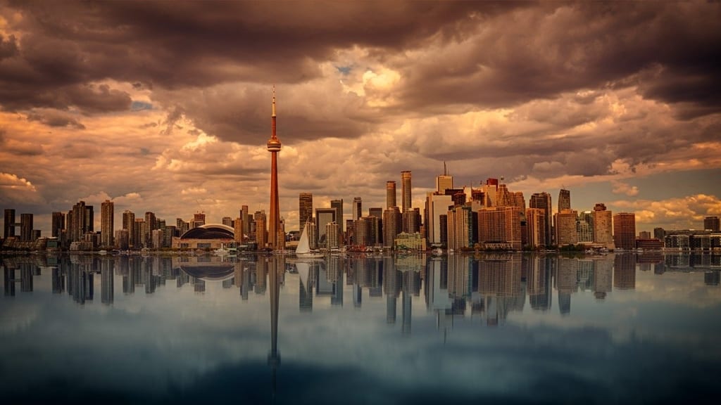 Toronto's skyline at waterfront with dark clouds above.