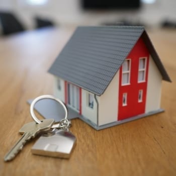 Tiny model of a red and white house next to a set of keys.