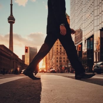 A man walking in Toronto with the CN Tower in the background.