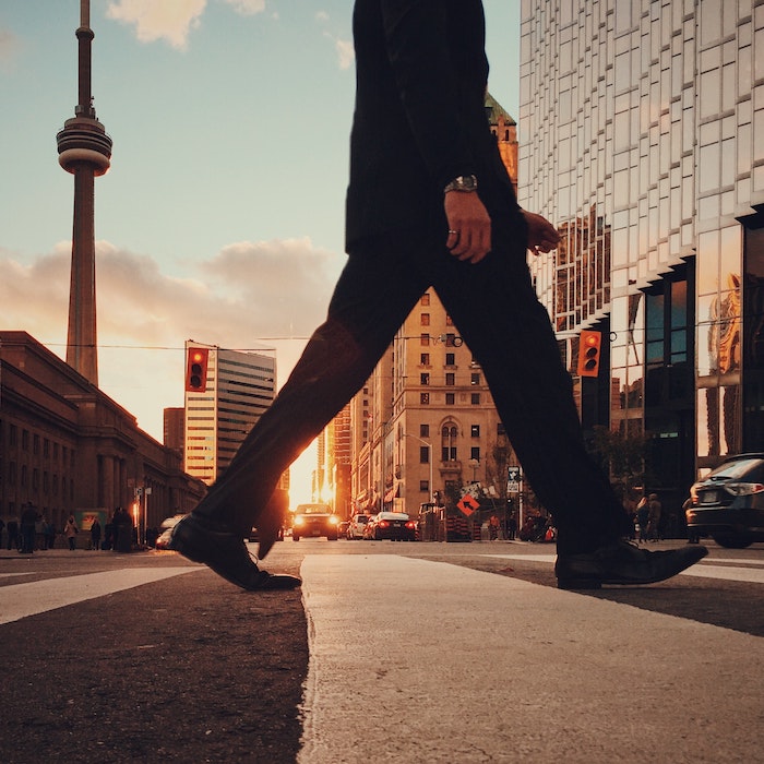 A man walking in Toronto with the CN Tower in the background.