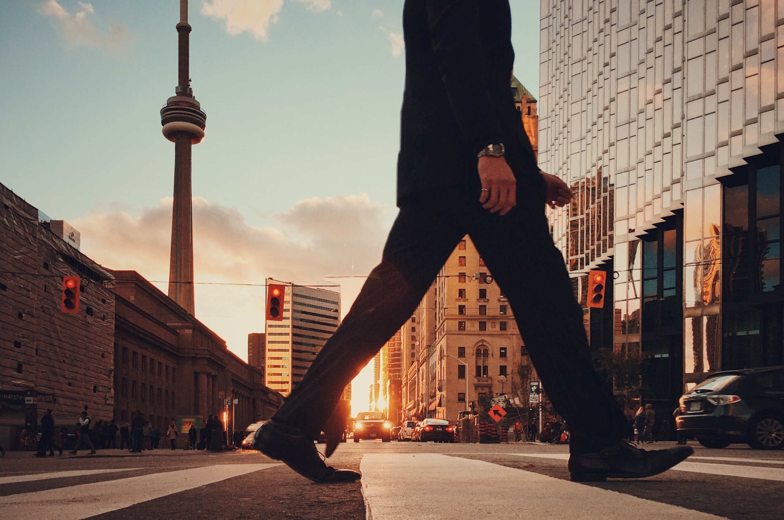 A man walking in Toronto with the CN Tower in the background. Photo by Arturo Castaneyra