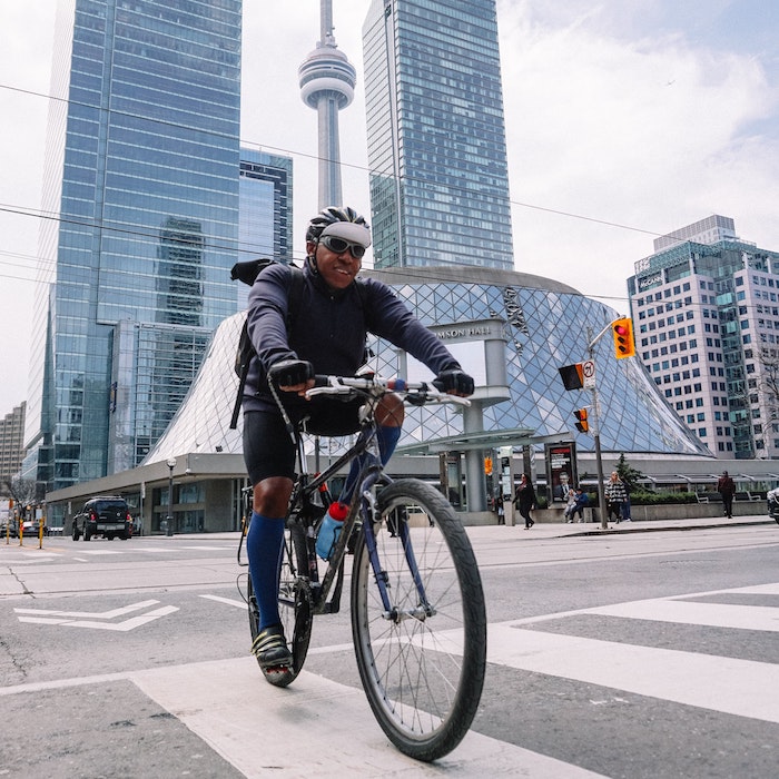 Man biking near the Roy Thomson Hall, Simcoe Street, Toronto, Toronto, ON, Canada with CN Tower in the background.