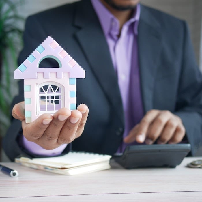 Person holding a small house indicating property purchase