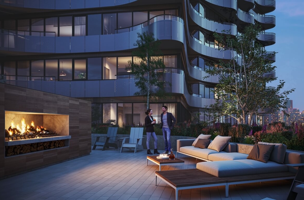 Outdoor terrace of a high-rise building with comfortable seating, a fireplace, and a view of the city at dusk.